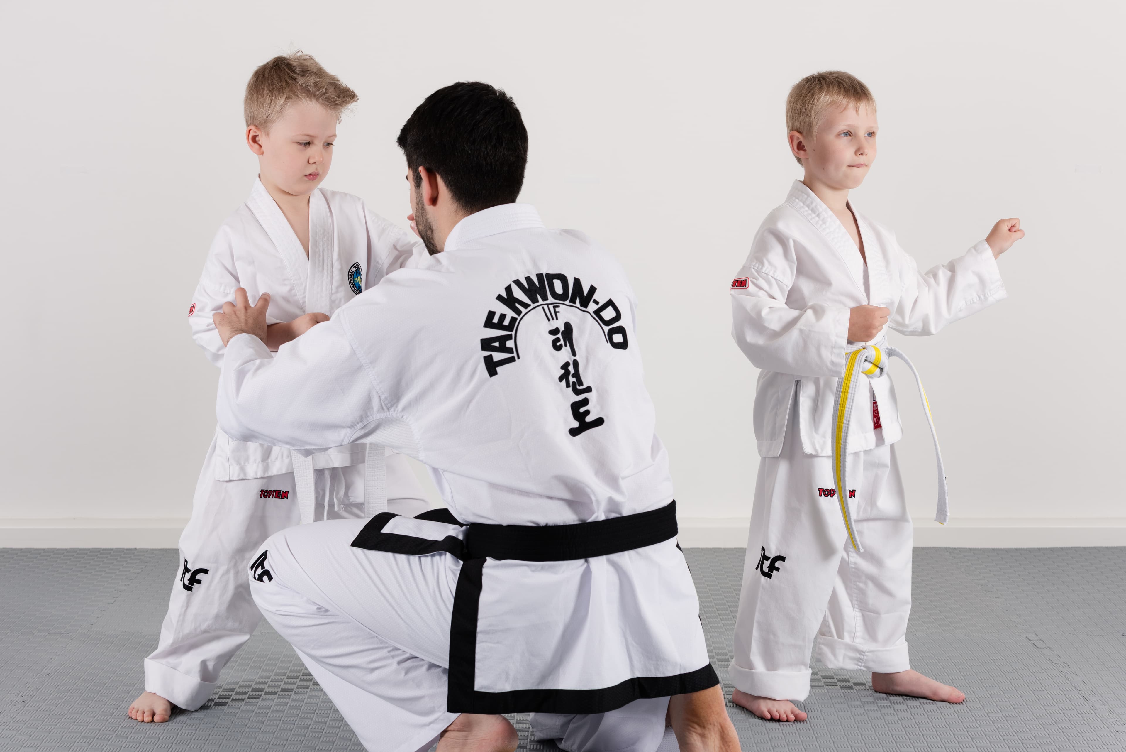 Ein Trainer korrigiert die Armhaltung eines Kindes beim gemeinsamen Training.